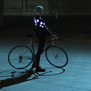 a girl with a bicycle wearing many reflective badges and they reflect light